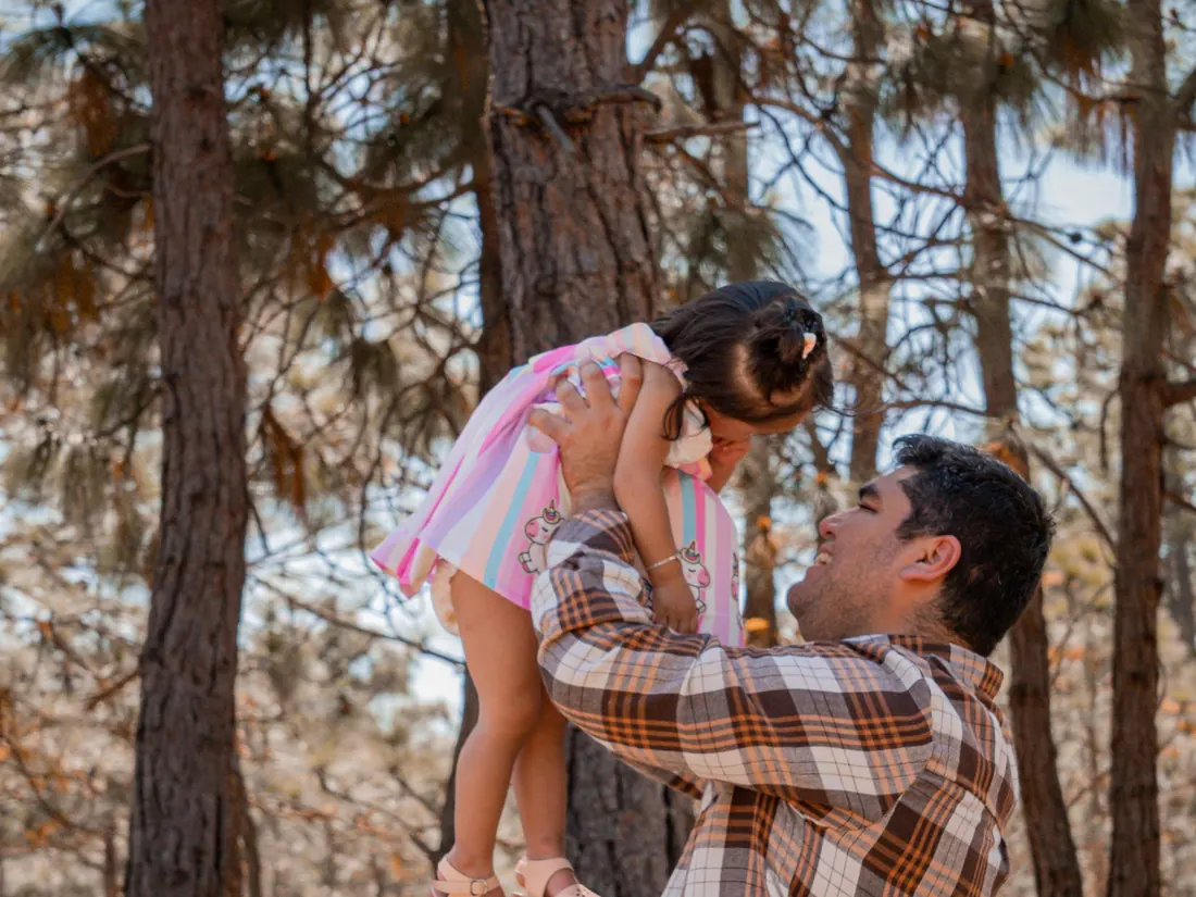 Papá cargando a su hija en el bosque